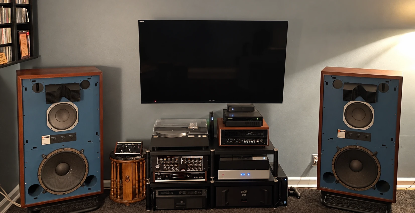 Vintage JBL studio monitors with a turntable and audio components in a home listening setup